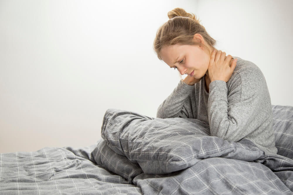 Donna a letto con rigidità mattutina, dolore al collo e cervicale Donna a letto con rigidità mattutina, dolore al collo e cervicale