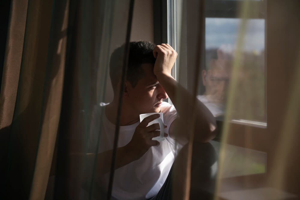 uomo-pensieroso-al-mattino Uomo pensieroso al mattino che riflette sulla stanchezza persistente e sulla mancanza di energia nonostante il riposo