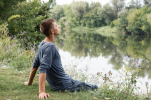 Uomo che pratica tecniche di rilassamento nella natura per ridurre lo stress cronico e il carico allostatico